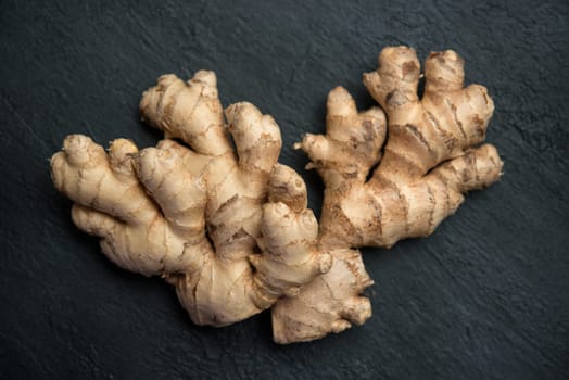 Flat lay fresh raw ginger root on dark background.