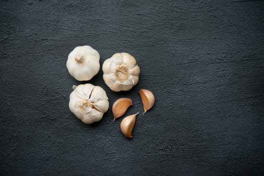 Top view garlic cloves and bulb with copy space on dark background.