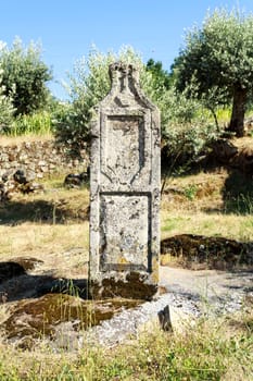 View of an ancient granite stone column by the side of the road near the roman bridge in the village of Mesquitela, Gouveia, Portugal