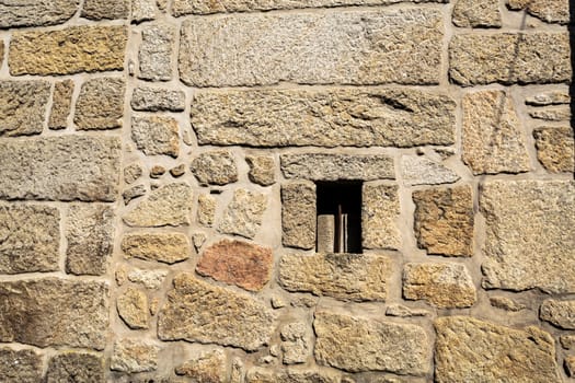 View of a wall showing the traditional granite stone masonry architecture and a ventilation slot of a house in the village of Mesquitela, Gouveia, Portugal