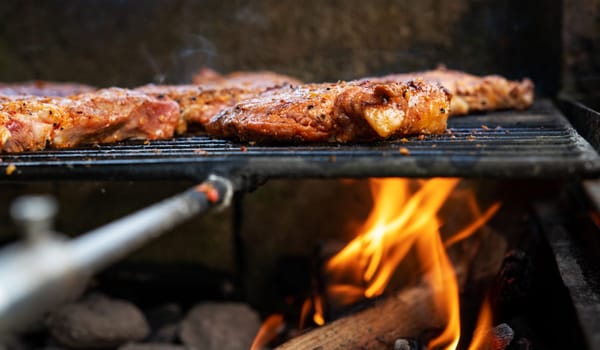 grilled pork with flames on charcoal barbecue