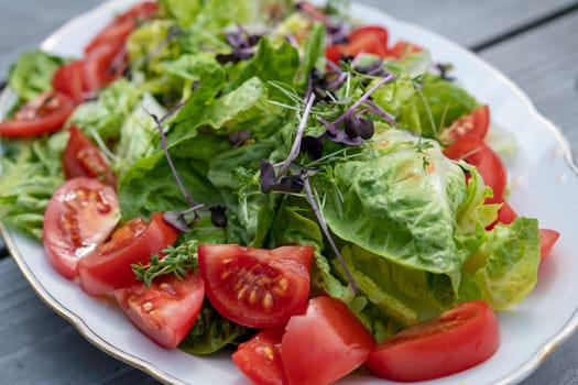 mixed summer salad on plate and wooden ground