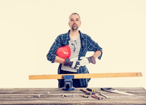 worker in blue plaid  shirt with red helmet on workbench