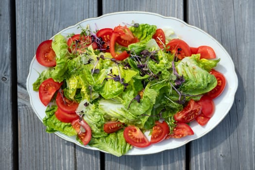 mixed summer salad on plate and wooden ground