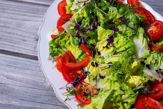 mixed summer salad on plate and wooden ground