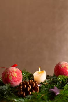 christmas decor with tree-balls, candle, branch and cone in front of golden background