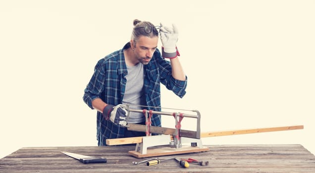 worker in blue plaid  shirt sawing wood