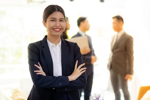 Portrait of asian businesswoman with business team in background at office window using for coporate working background