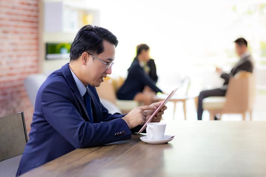 Portrait of Businessman working in cafe using smart phone tablet with business team in background using for coporate background work
