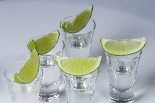 Tequila in glass with lime on white background