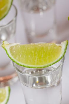 Tequila in glass with lime on white background