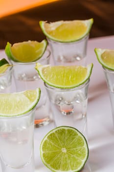 Tequila shot with a slice of lime on the glass on orange background. Selective Focus