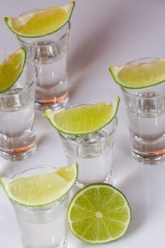 Tequila in glass with lime on white background