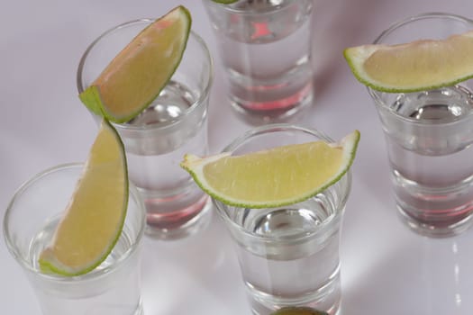 Tequila in glass with lime on white background
