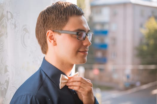 Portrait of young groom tying bow tie while getting ready for wedding
