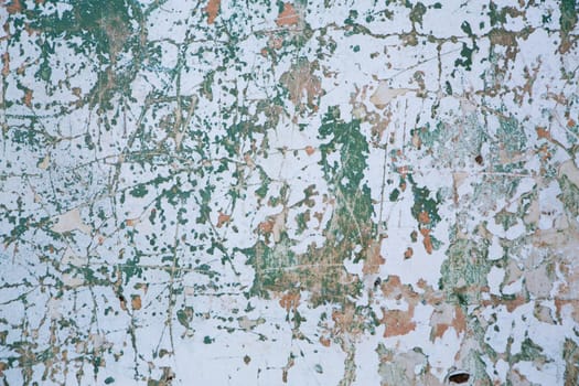Grunge wall texture background. Paint cracking off dark wall with rust underneath.