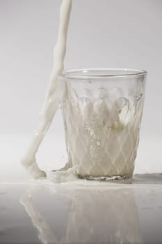pouring milk in a glass isolated against white background