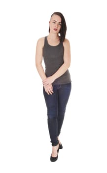 A beautiful young woman standing on white background in jeans and.a t-shirt with short black hair and her hands on her tight.