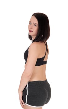 A beautiful young woman standing in black sportswear from the back,.looking over her shoulder, isolated for white background.