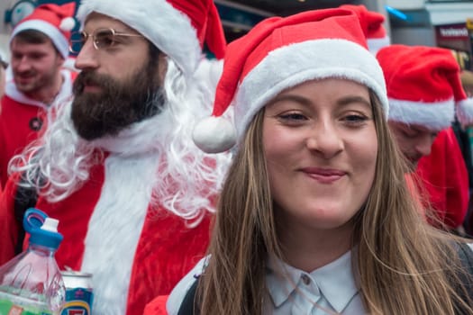 London, UK - December 2018 :Happy smiling girl dressed in santa outfit and taking part in a themed SantaCon event