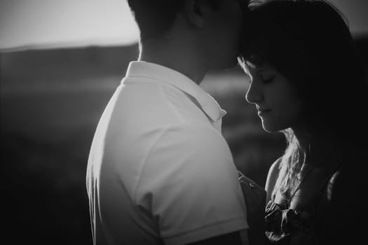 Black white photography romantic couple standing and kissing on background summer meadow sunset