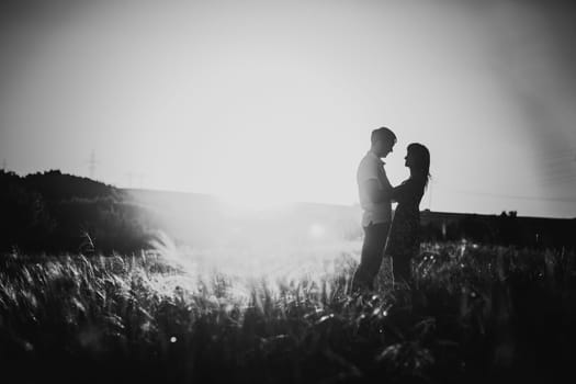 Black white photography romantic couple standing and kissing on background summer meadow sunset