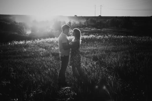 Black white photography romantic couple standing and kissing on background summer meadow sunset
