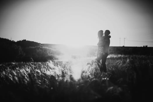 Black white photography romantic couple standing and kissing on background summer meadow sunset