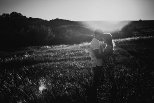 Black white photography romantic couple standing and kissing on background summer meadow sunset