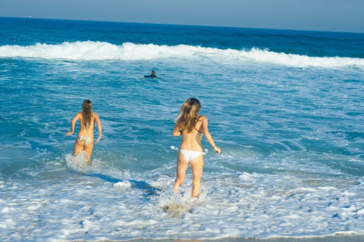 two beautiful young girls running in the sea