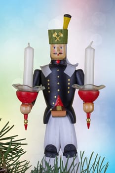Christmas decoration background. Closeup of a christmas vintage wooden traditional figurine with two candles against abstract pastel bokeh background. Card concept.