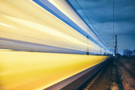 Railroad track at night. Light trails of passenger train.