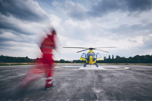 Alarm for helicopter emergency medical service. Paramedic running to helicopter on heliport.