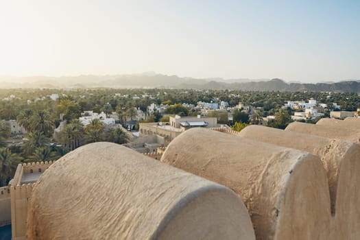 City against mountain range at idyllic sunset. Nizwa in Sultanate of Oman.