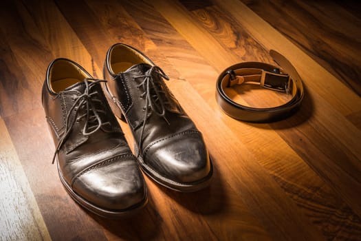 Stylish Black Handcrafted Dress Shoes and Leather Belt on Wooden Floor Spotlight Sun Clothing