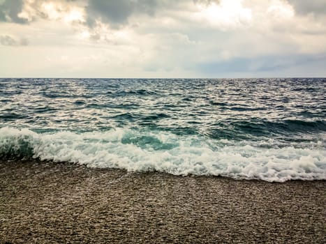 Foamy waves on a stony beach on a cloudy winter day