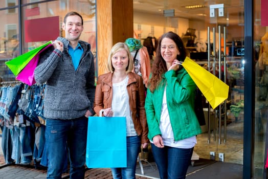two women and a man in front of clothes shop