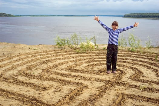 The girl rejoices in reaching the center of the labyrinth on sand