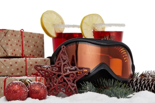 Winter holidays still life with gift boxes, fir tree branch, ski glasses, mulled wine and Christmas decorations lying on snow on a white background. New Year and Christmas. Winter vacation.