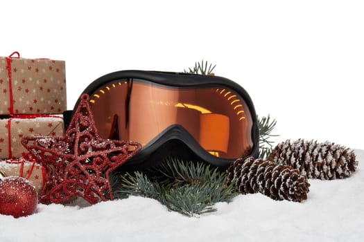 Winter holidays still life with gift boxes, fir tree branch, ski glasses and Christmas decorations lying on snow on a white background. New Year and Christmas. Winter vacation.