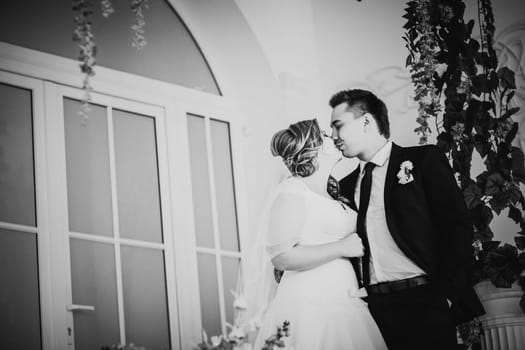 Black white photography bride and groom posing in a hotel room on background windows