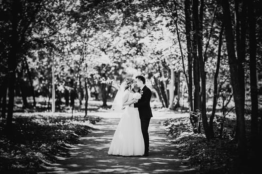Black white photography happy couple bride and groom embracing they stand in a forest full length