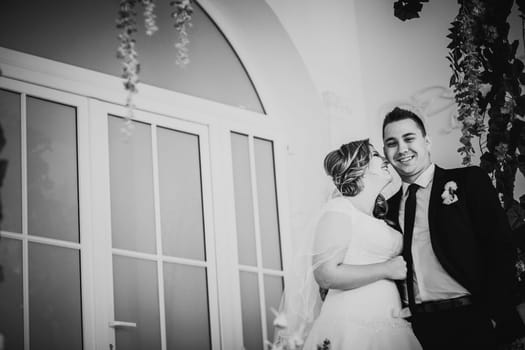 Black white photography bride and groom posing in a hotel room on background windows