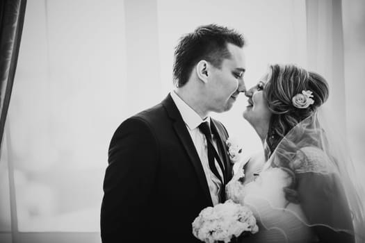 Black white photography bride and groom posing in a hotel room on background windows