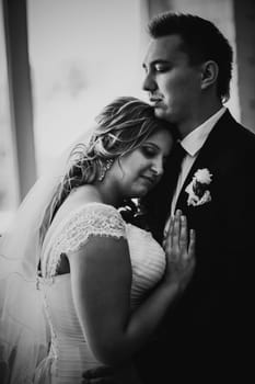 Black white photography bride and groom posing in a hotel room on background windows