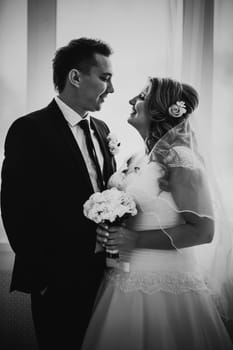 Black white photography bride and groom posing in a hotel room on background windows