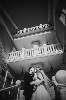 Black white photography bride and groom embracing they stand on background beautiful architecture of the city full length