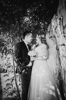 Black white photography happy couple bride and groom embracing they stand on background stone wall close-up