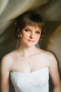 portrait of a beautiful young bride on the background of beautiful fabrics