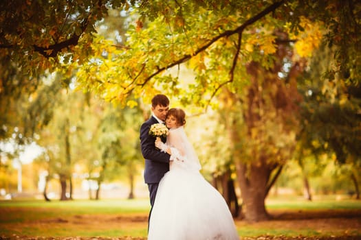 young bride and groom on the background of autumn landscape